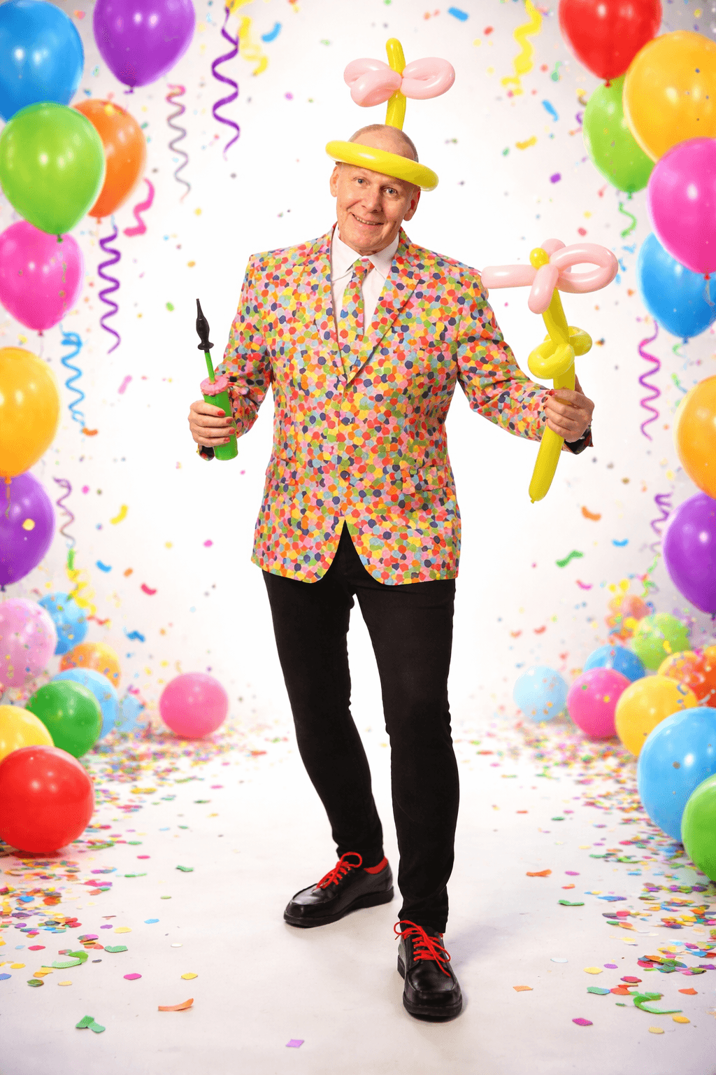 Mand i farverig jakke med balloner og konfetti.